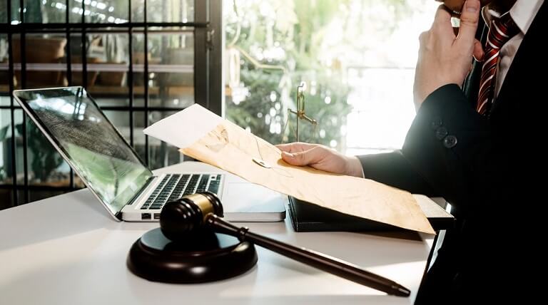 איש לבוש בחליפה ובעניבה קורא מסמכים מול מחשב נייד